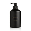 A matte black pump bottle of Häxan Heretic Body Lotion, featuring gold lettering on the front, set against a clean white background.