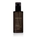 A dark black translucent pump bottle of Häxan Body Oil with a black cap, centered on a white background.