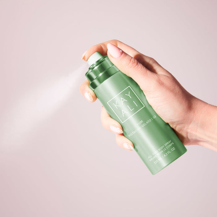 Hand holding a green spray bottle labeled 'KAYALI' against a light background